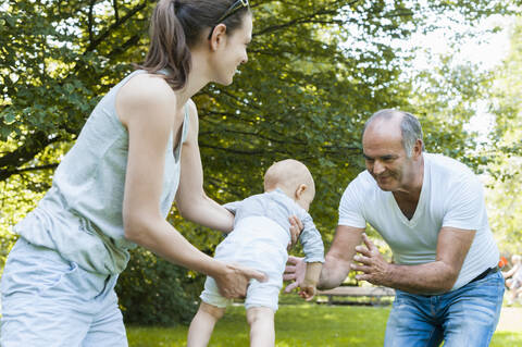 Senior man spending time with his adult daughter and his granddaughter in a park stock photo