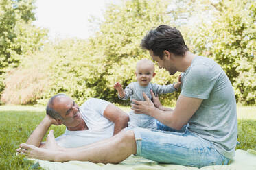 Älterer Mann verbringt Zeit mit seinem erwachsenen Sohn und seiner Enkelin in einem Park - DIGF10247