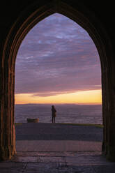 Frau beobachtet den Sonnenaufgang vom Glastonbury Tor, Somerset, England, Vereinigtes Königreich, Europa - RHPLF14677