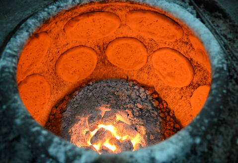 Fladenbrotbacken im Fladenbrotbackofen auf dem Nachtmarkt in der Turfan-Straße, Turfan, Xinjiang, China, Asien - RHPLF14737