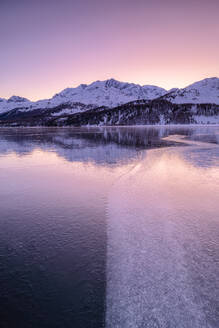 Die Farben des Sonnenaufgangs spiegeln sich auf der eisigen Oberfläche des Silsersees, Engadin, Graubünden, Schweizer Alpen, Schweiz, Europa - RHPLF14838