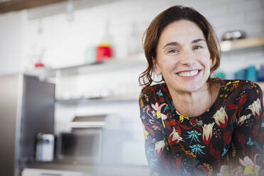 Porträt selbstbewusste lächelnde brünette Frau in der Küche - CAIF26958