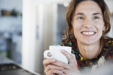 Portrait smiling brunette woman drinking coffee - CAIF26988