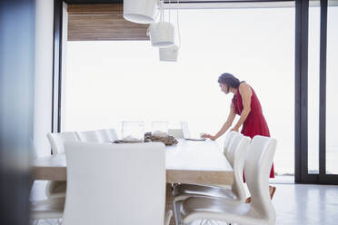 Woman working at laptop in dining room - CAIF27002