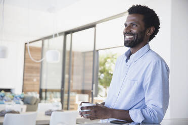 Smiling man drinking coffee, looking away - CAIF27021