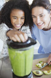 Mutter und Tochter machen einen gesunden grünen Smoothie im Mixer - CAIF27040