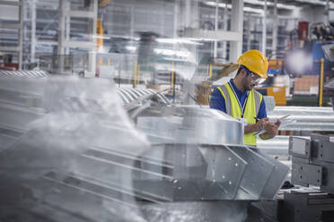 Fabrikarbeiter mit Klemmbrett bei der Kontrolle von Stahlteilen in einer Fabrik - CAIF27055