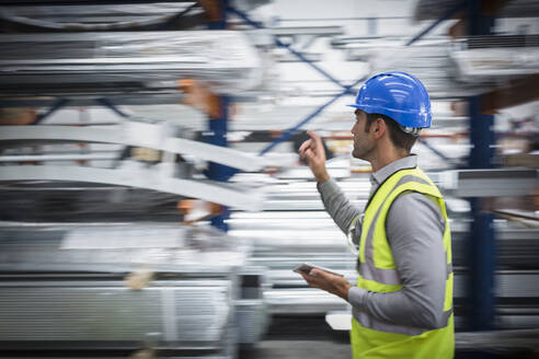 Male worker with digital tablet checking inventory in warehouse - CAIF27066