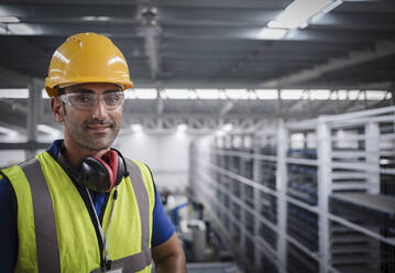 Portrait männlicher Arbeiter mit Gehörschutz in einer Fabrik - CAIF27072