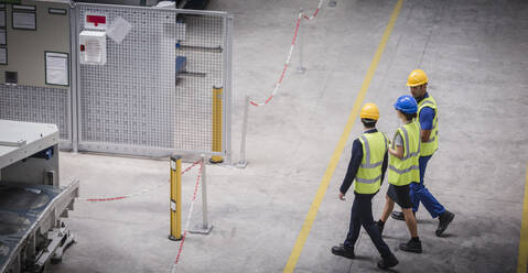 Arbeiter gehen und sprechen in einer Fabrik - CAIF27078