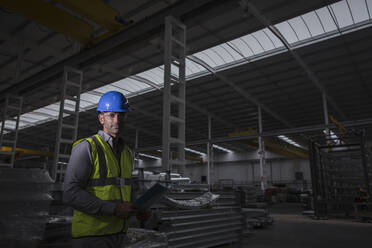 Portrait serious, confident male worker in dark steel factory - CAIF27082