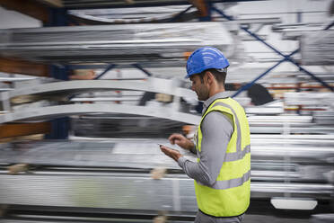 Männlicher Arbeiter mit digitalem Tablet in einem Stahlwerk - CAIF27091