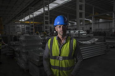 Porträt eines selbstbewussten, ernsten Arbeiters in einer dunklen Stahlfabrik - CAIF27092