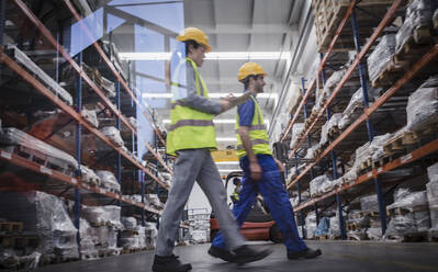 Workers with clipboard walking in warehouse - CAIF27107