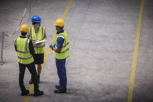 Vorgesetzter und Arbeiter mit Klemmbrett im Gespräch in einer Fabrik - CAIF27108