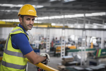 Portrait confident male supervisor leaning on platform railing in factory - CAIF27125
