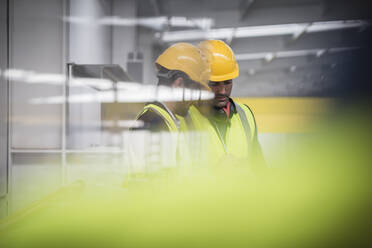 Male supervisors talking, looking down in factory - CAIF27138