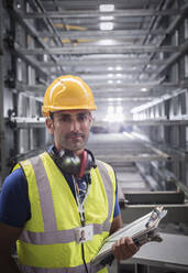 Portrait serious, confident male supervisor with clipboard in steel factory - CAIF27157