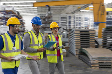 Supervisor and workers with clipboard and digital tablet walking in factory - CAIF27158