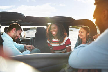 Laughing young friends enjoying road trip in jeep - CAIF27170