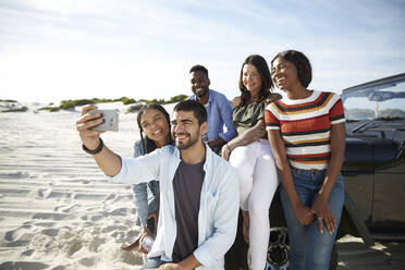 Junge Freunde mit Fotohandy machen ein Selfie am Strand - CAIF27177