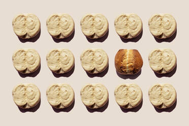 Studio shot of rows of raw dough lumps and single baked bread - GEMF03636