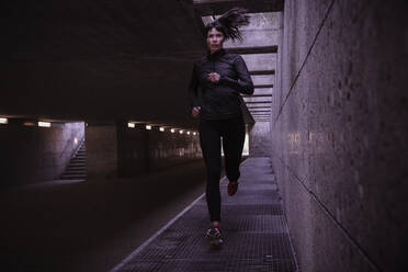 Weibliche Athletin läuft durch eine Fußgängerunterführung - DHEF00178