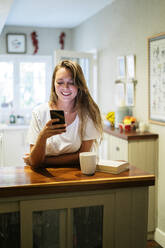 Young woman using smartphone in the kitchen - MPPF00872