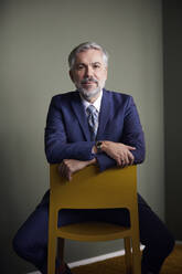 Portrait of confident mature businessman sitting on a chair - RBF07649