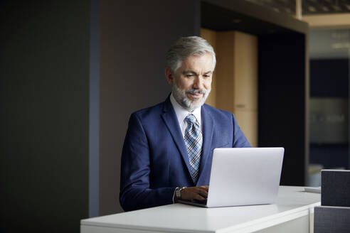 Älterer Geschäftsmann mit Laptop im Büro - RBF07655