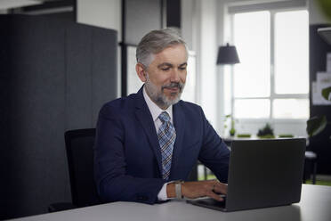 Älterer Geschäftsmann mit Laptop im Büro - RBF07669