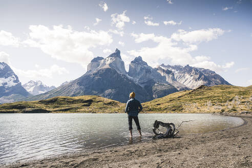 Wanderer in Gebirgslandschaft beim Waten in einem See im Torres del Paine National Park, Patagonien, Chile - UUF20249