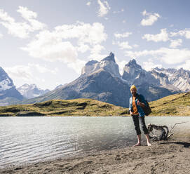 Happy man in mountainscape at lakeside in Torres del Paine National Park, Patagonia, Chile - UUF20252