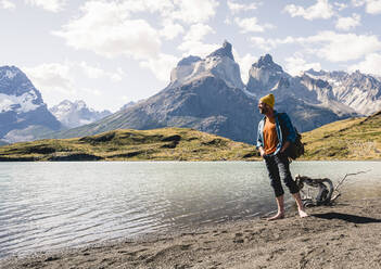Happy man in mountainscape at lakeside in Torres del Paine National Park, Patagonia, Chile - UUF20253