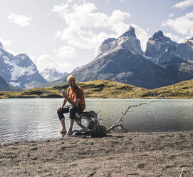 Mann hält Handy in Berglandschaft am Seeufer im Torres del Paine National Park, Patagonien, Chile - UUF20260