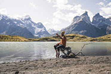 Happy man taking a selfie in mountainscape at lakeside in Torres del Paine National Park, Patagonia, Chile - UUF20261