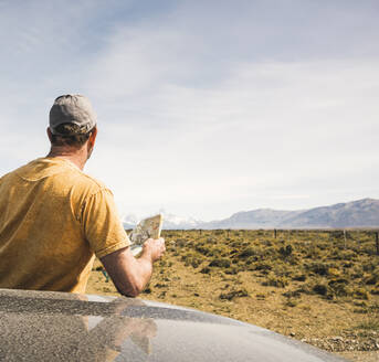 Rear view of man with map at car in remote landscape in Patagonia, Argentina - UUF20278