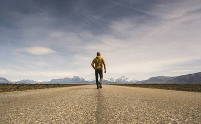 Man walking on a road in remote landscape in Patagonia, Argentina - UUF20284