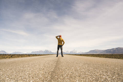 Mann steht auf einer Straße in einer abgelegenen Landschaft in Patagonien, Argentinien, lizenzfreies Stockfoto