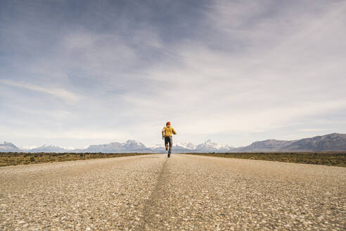 Mann läuft auf einer Straße in abgelegener Landschaft in Patagonien, Argentinien - UUF20291