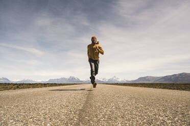 Mann läuft auf einer Straße in abgelegener Landschaft in Patagonien, Argentinien - UUF20292