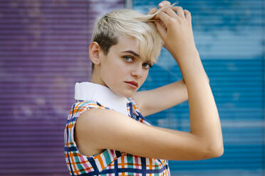 Portrait of female teenager wearing colorful dress with multicolored glass wall in the background - TCEF00556