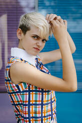 Portrait of female teenager wearing colorful dress with multicolored glass wall in the background - TCEF00557