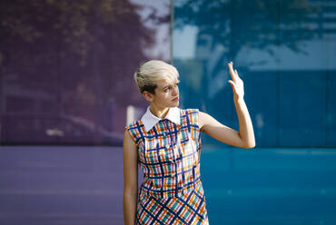 Portrait of female teenager wearing colorful dress with multicolored glass wall in the background - TCEF00558