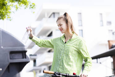 Junge Frau wirft Müll in die Recycling-Tonne - SGF02603