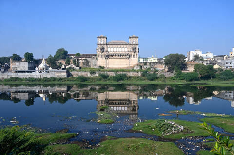 The 18th century Naulakha Palace facade reflected in the still waters of the Gondal River, Gondal, Gujarat, India, Asia stock photo