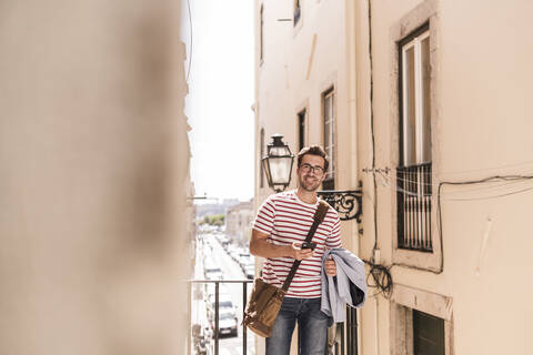 Smiling young man with smartphone in the city, Lisbon, Portugal stock photo