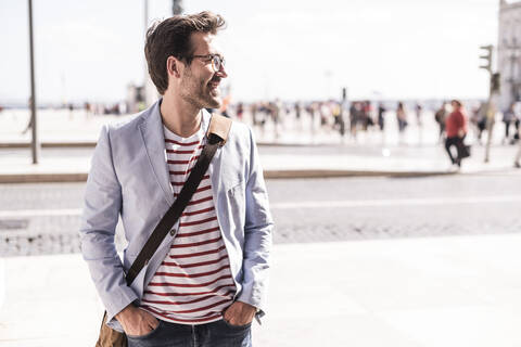 Lächelnder junger Mann in der Stadt, der zur Seite blickt, Lissabon, Portugal, lizenzfreies Stockfoto