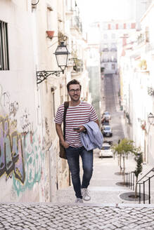 Junger Mann beim Treppensteigen in der Stadt, Lissabon, Portugal - UUF20350