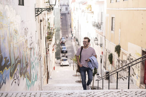 Junger Mann beim Treppensteigen in der Stadt, Lissabon, Portugal - UUF20351